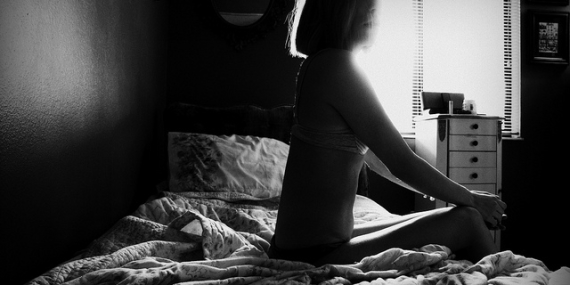 Femme assise sur un lit, en noir et blanc