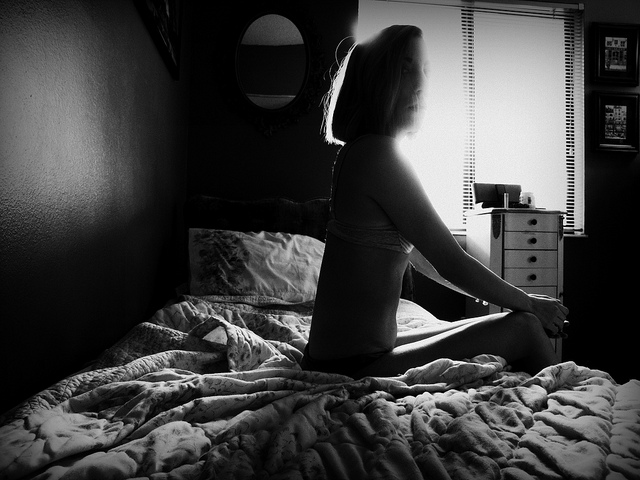 Femme assise sur un lit, en noir et blanc