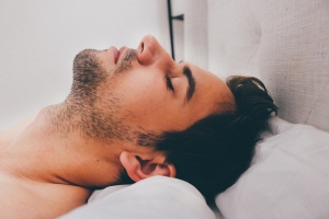 Homme tête posée sur un oreiller blanc.