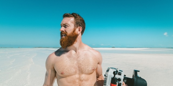 Photographie d'un homme torse nu sur une plage paradisiaque.