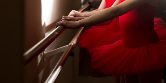 Jeunes danseuses à la barre dans des tutus rouge.