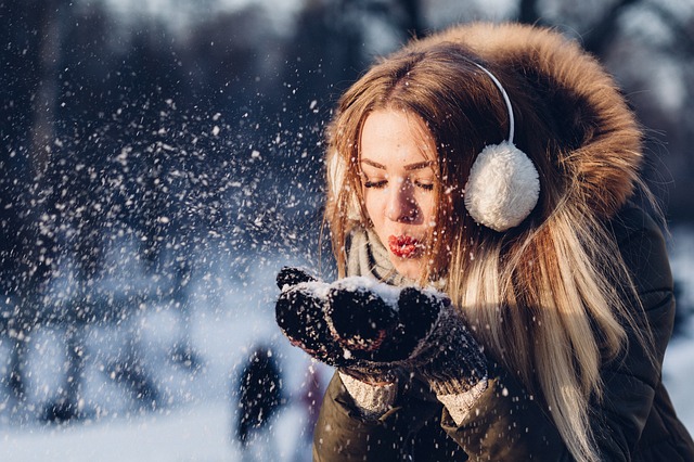Jeune femme qui souffle dans la neige.