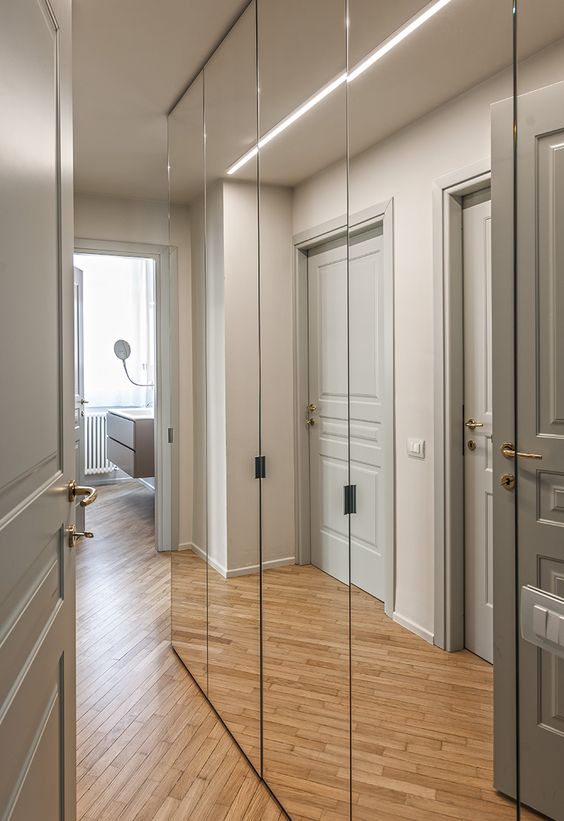 Des portes de placards avec miroirs dans un couloir.