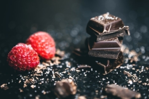 Carrés de chocolat avec deux framboises.