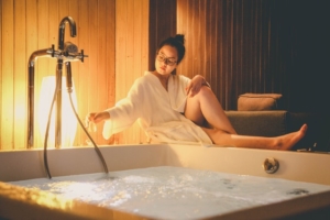 Jeune femme qui prépare un bain bouillonant dans son spa.