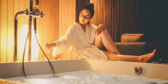 Jeune femme qui prépare un bain bouillonant dans son spa.