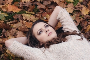 Jeune femme qui se repose sur un lit de feuilles mortes.