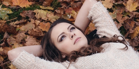 Jeune femme qui se repose sur un lit de feuilles mortes.