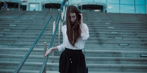 JEune femme descendant des escaliers en short noir et chemise blanche.