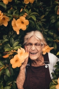 Femme âgée dans un buisson de fleurs.