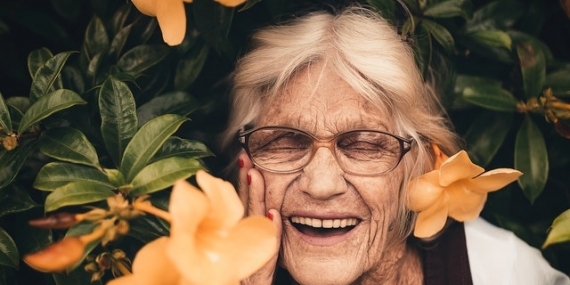 Femme âgée dans un buisson de fleurs.